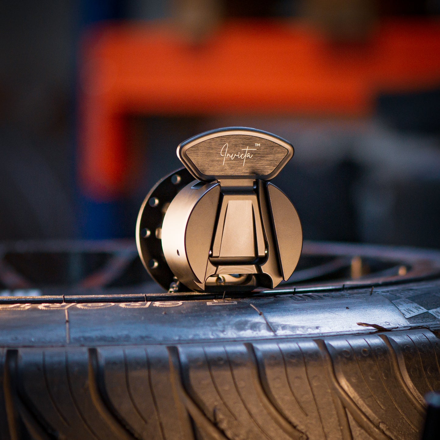 Asetek Simsports Invicta™ Quick Release Adapter positioned on a racing tire in a workshop setting.